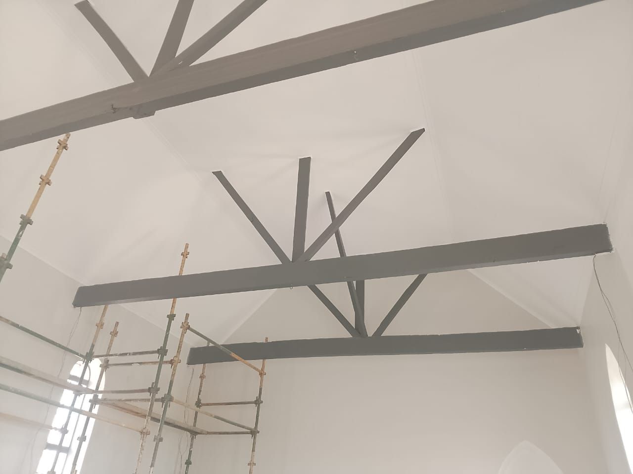 New grey roof trusses spanning the white ceiling inside the church