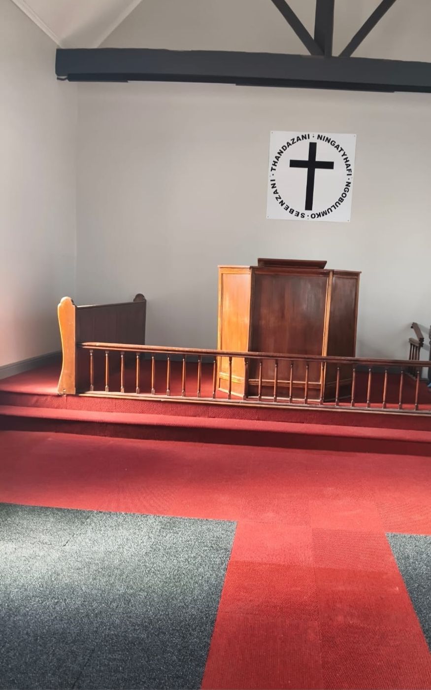 The sanctuary — wooden pulpit, cross emblem on the wall and red carpet